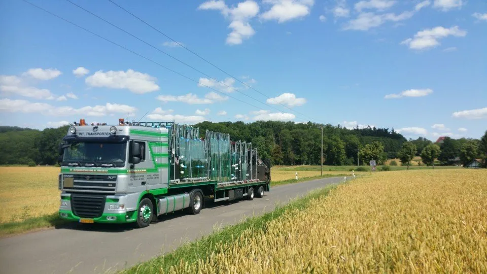Vrachtwagen met glasrekken langs een graanveld